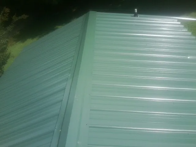 New green metal panels meeting at the ridge of a roof — Flat Roof Repair work by our crew in Sapelo Island