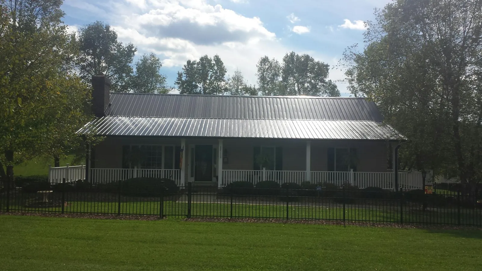 Gray metal roof on a brick ranch with a full width front porch — Gutter Guard Installation work by our crew in Sapelo Island
