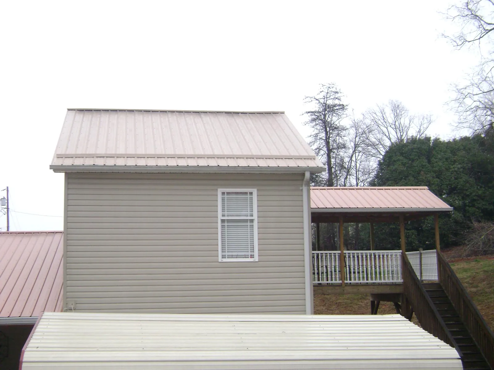 Tan metal roofs on a two story addition and attached porch, from a Roof Replacement job in Sapelo Island