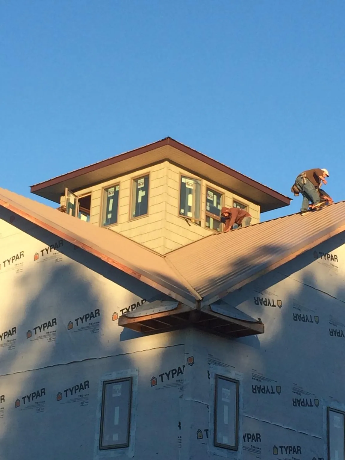 Roofers working around a rooftop cupola on a new metal roof at sunset — Roof Waterproofing in Sapelo Island by Roofing Brothers